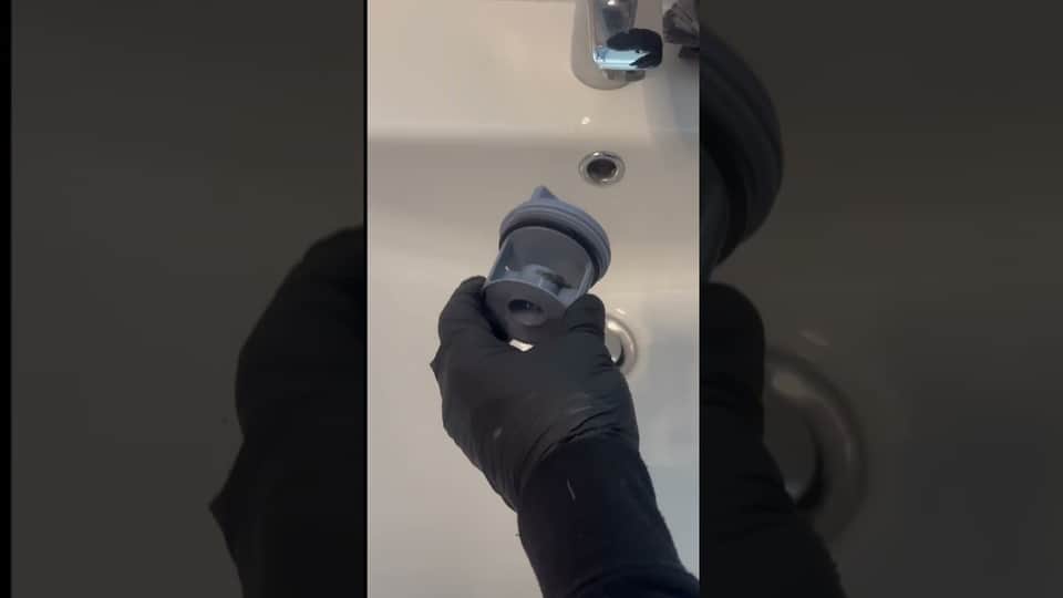 Geöffnetes Flusensieb einer Waschmaschine vor der Reinigung